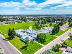 Expansive property featuring a large institutional building with a flat roof and numerous windows, surrounded by vast green spaces - 
