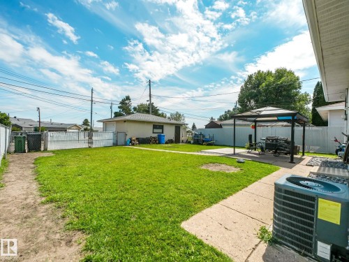 Spacious backyard featuring a manicured lawn, concrete patio, and detached garage - 13323 58 Street Nw, Edmonton, AB - Outdoor