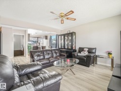 Open-concept living space featuring wood-finish flooring, a ceiling fan, and light-toned walls - 