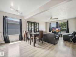 Open-concept living and dining area featuring wood-finish flooring and multiple windows - 