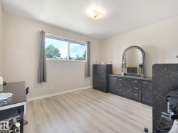 Spacious room featuring light-toned walls, wood-finish flooring, a contemporary ceiling light fixture, and a large window providing natural illumination - 