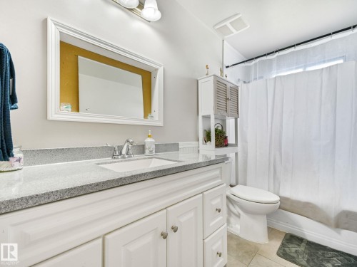Bathroom vanity featuring a single basin sink, chrome faucet, and stone-finish countertop - 13323 58 Street Nw, Edmonton, AB - Indoor Photo Showing Bathroom