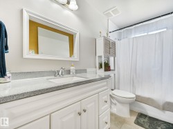 Bathroom vanity featuring a single basin sink, chrome faucet, and stone-finish countertop - 