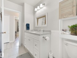 Bathroom featuring a white shaker-style vanity with a light-colored countertop, an undermount sink, and a chrome faucet - 