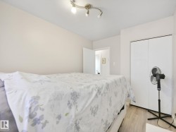 Bedroom featuring light-toned walls, track lighting, and wood-finish flooring - 