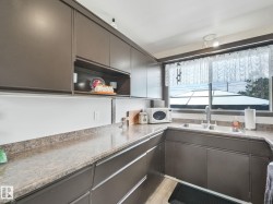 Kitchen featuring extensive dark cabinetry, a double basin stainless steel sink, and durable laminate countertops - 