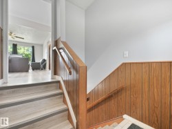 Split-level entry featuring wood-finish flooring on stairs and a wood-paneled wall - 