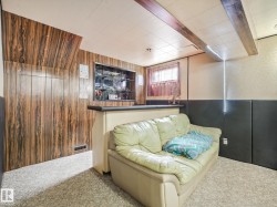 Entertainment area featuring a built-in bar with display shelving, wood-finish paneling, drop ceiling, and light-colored carpet flooring - 