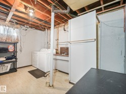Laundry area featuring an exposed beam ceiling, utility sink, and light-toned flooring - 