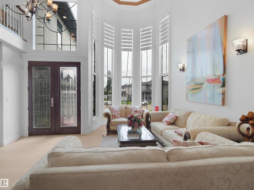 Grand entryway featuring double doors with leaded glass, an arched transom window, and light wood-finish flooring - 3136 35 Avenue Nw, Edmonton, AB - Indoor Photo Showing Living Room