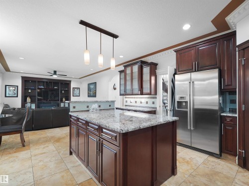 Kitchen island with a light-toned countertop, dark wood-finish cabinetry, and pendant lighting - 3136 35 Avenue Nw, Edmonton, AB - Indoor Photo Showing Kitchen