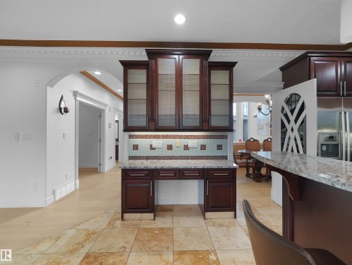 Built-in cabinetry with frosted glass doors, a granite countertop, and a tiled backsplash - 3136 35 Avenue Nw, Edmonton, AB - Indoor Photo Showing Kitchen