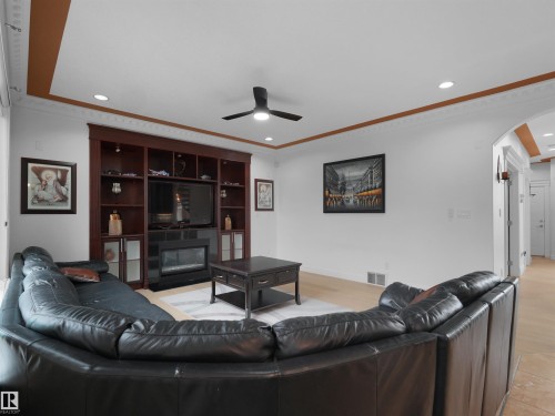 Living area featuring a built-in entertainment center with integrated fireplace, recessed lighting, ceiling fan, crown molding, and light wood-finish flooring - 3136 35 Avenue Nw, Edmonton, AB - Indoor