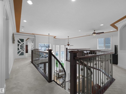 Upper-level hallway featuring light-toned carpeting, decorative crown molding, recessed lighting, and a striking glass-paneled door - 3136 35 Avenue Nw, Edmonton, AB - Indoor Photo Showing Other Room