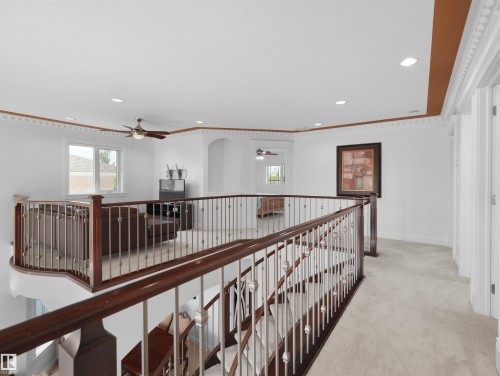 Upper-level landing with dark wood railings and metal balusters overlooking a sunken space - 3136 35 Avenue Nw, Edmonton, AB - Indoor Photo Showing Other Room