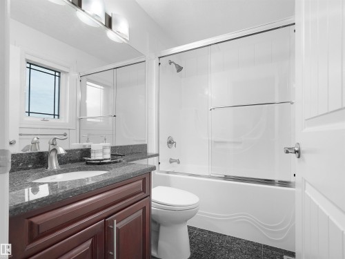Bathroom featuring a dark wood-finish vanity with a stone countertop, an undermount sink, and a framed mirror - 3136 35 Avenue Nw, Edmonton, AB - Indoor Photo Showing Bathroom