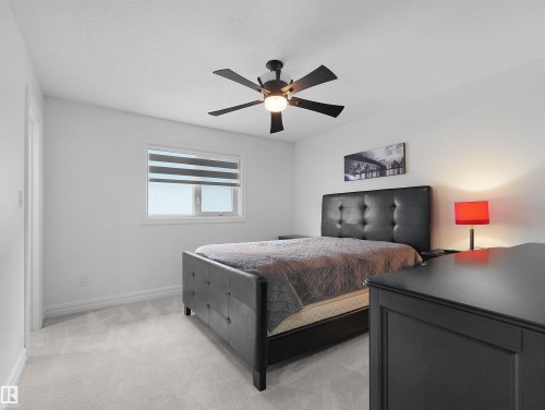Carpeted room featuring a ceiling fan with integrated lighting, a window with horizontal blinds, and a built-in closet with a white door - 3136 35 Avenue Nw, Edmonton, AB - Indoor Photo Showing Bedroom