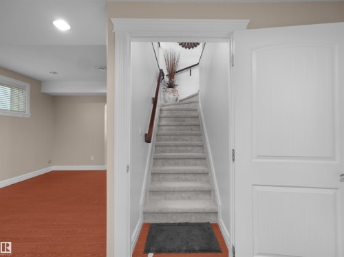 Carpeted staircase with wood handrail, white trim, and neutral wall tones - 3136 35 Avenue Nw, Edmonton, AB - Indoor Photo Showing Other Room