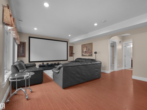 Entertainment room featuring a large projection screen, recessed lighting, wood-finish flooring, and an arched doorway - 3136 35 Avenue Nw, Edmonton, AB - Indoor
