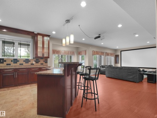 Kitchenette featuring rich wood cabinetry, stone countertops, and a decorative tile backsplash - 3136 35 Avenue Nw, Edmonton, AB - Indoor Photo Showing Kitchen