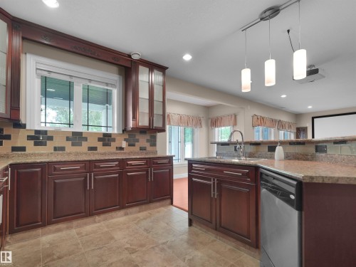 Kitchen featuring rich wood-finish cabinetry, granite-style countertops, and a decorative tile backsplash - 3136 35 Avenue Nw, Edmonton, AB - Indoor Photo Showing Kitchen