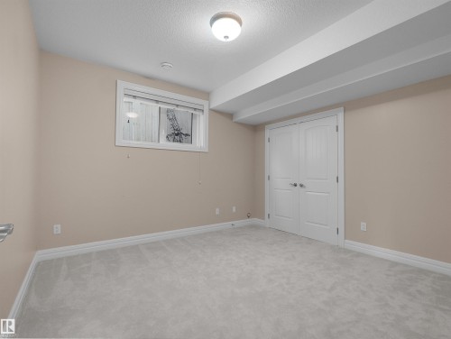 Carpeted room with a flush-mount ceiling light fixture, white trim, and a double-door closet - 3136 35 Avenue Nw, Edmonton, AB - Indoor Photo Showing Other Room