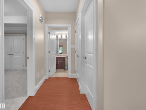 Hallway featuring wood-finish flooring, light neutral walls, white trim, and white paneled doors - 3136 35 Avenue Nw, Edmonton, AB - Indoor Photo Showing Other Room