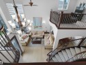 Two-story living area featuring a grand chandelier, light wood-finish flooring, a curved staircase with carpeted treads and dark wood banisters, and a second-story balcony with metal balusters - 3136 35 Avenue Nw, Edmonton, AB  - Indoor Photo Showing Other Room 