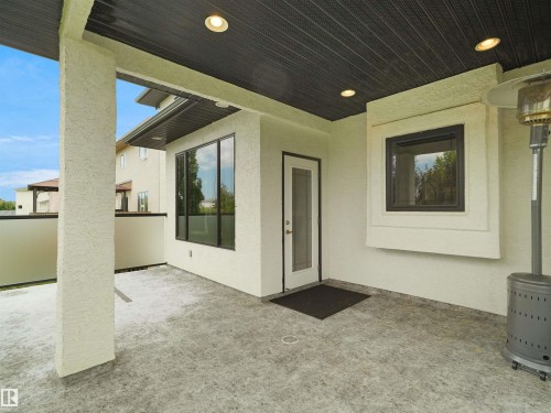 Covered outdoor patio featuring a textured concrete floor, recessed lighting, and an exterior door with a glass insert - 3136 35 Avenue Nw, Edmonton, AB - Outdoor With Deck Patio Veranda With Exterior