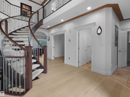 Grand entryway featuring a curved staircase with dark wood banisters and metal balusters - 3136 35 Avenue Nw, Edmonton, AB - Indoor Photo Showing Other Room