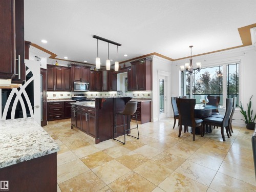 Gourmet kitchen featuring rich wood cabinetry, light-toned stone countertops, and integrated stainless steel appliances - 3136 35 Avenue Nw, Edmonton, AB - Indoor