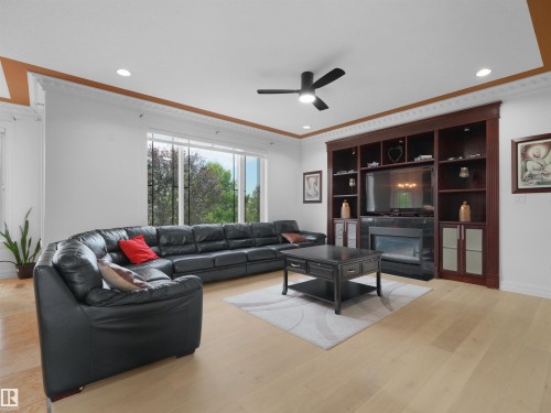 Spacious living area featuring light wood-finish flooring and a built-in entertainment center with an electric fireplace - 3136 35 Avenue Nw, Edmonton, AB - Indoor Photo Showing Living Room