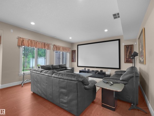 Dedicated media room featuring a large projection screen, recessed ceiling lighting, and wood-finish flooring - 3136 35 Avenue Nw, Edmonton, AB - Indoor Photo Showing Other Room