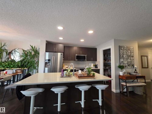 Kitchen island featuring a light-toned countertop with integrated seating for four - 491 Ebbers Way, Edmonton, AB 