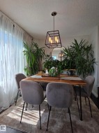 Dining area featuring wood-finish flooring, a contemporary geometric pendant light, and sheer window treatments - 