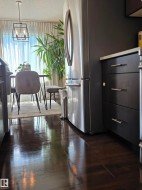 Stainless steel refrigerator and dark wood-finish cabinetry with silver hardware - 