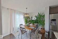 Dining area featuring wood-finish flooring, a contemporary chandelier, and a large window with sheer and blackout drapery - 