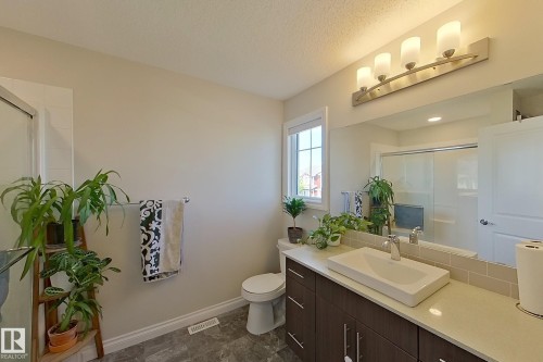 Bathroom featuring a dark wood-finish vanity with a vessel sink, a full-width mirror, and a four-light fixture - 491 Ebbers Way, Edmonton, AB 