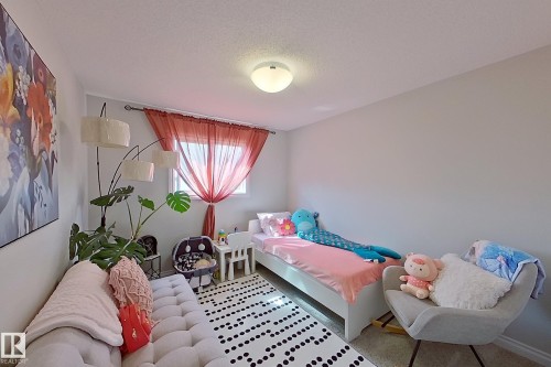 Room featuring a single window with sheer drapes, textured wall-to-wall carpeting, and a ceiling-mounted light fixture - 491 Ebbers Way, Edmonton, AB 