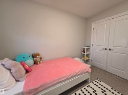 Bedroom with light gray walls, textured ceiling, and neutral-toned carpeting - 