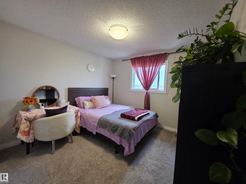 Bedroom featuring neutral wall paint, carpeted flooring, a flush-mount ceiling light, and a window with sheer drapes - 491 Ebbers Way, Edmonton, AB 