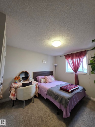 Carpeted room featuring a window with a white frame, a built-in ceiling light fixture, and neutral-toned walls - 491 Ebbers Way, Edmonton, AB 