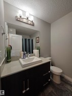 Bathroom featuring a dark wood-finish vanity with an undermount vessel sink, light countertop, and subway tile backsplash - 