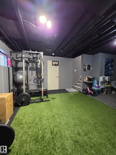 Versatile lower-level space featuring a turf floor area and dedicated exercise equipment zone - 491 Ebbers Way, Edmonton, AB 
