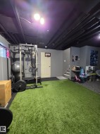 Versatile lower-level space featuring a turf floor area and dedicated exercise equipment zone - 