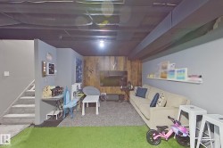 Finished lower level featuring a combination of gray painted walls and wood-panel accent wall - 