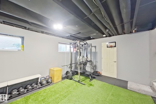 Finished basement space with light grey walls and a dark open ceiling - 491 Ebbers Way, Edmonton, AB 