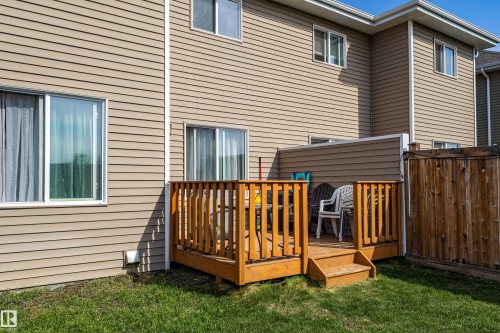 Rear exterior featuring a wooden deck with railing, stairs, and privacy fence - 491 Ebbers Way, Edmonton, AB 