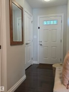 Entryway featuring dark wood-finish flooring and a white paneled front door with a transom window - 