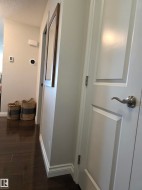 Hallway featuring dark wood-finish flooring, white walls, and white trim - 